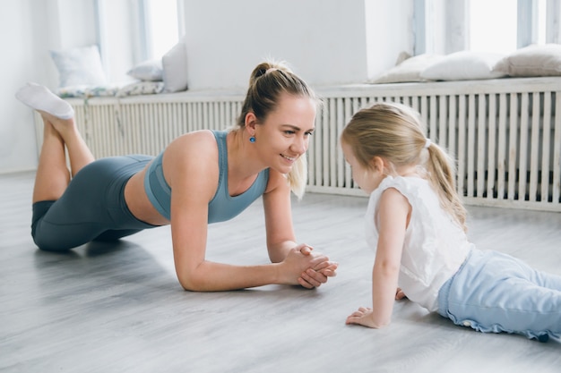 Mother and baby girl do exercises together in the gym