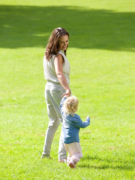 Mother and baby girl walking on grass