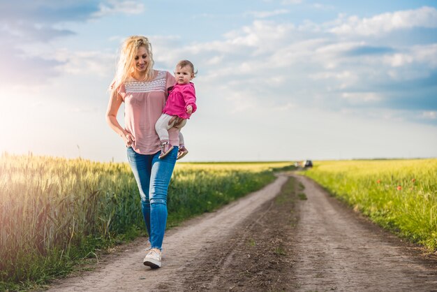 Mother and baby girl walking on the gravel road