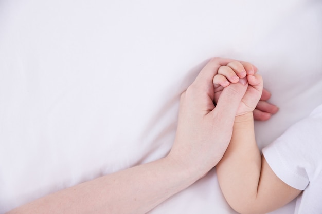 Photo mother and baby holding hands