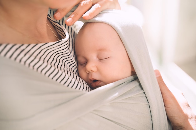 Madre e bambino sulla natura all'aperto baby in wrap carrier donna che trasporta piccolo bambino in fascia per bambini