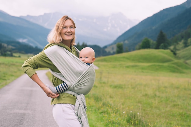 Mother and baby on nature outdoors Baby in wrap carrier Woman carrying little child in baby sling
