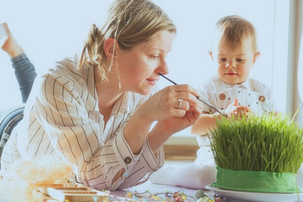 Mother and baby painting Easter eggs at home Happy family preparing for Easter