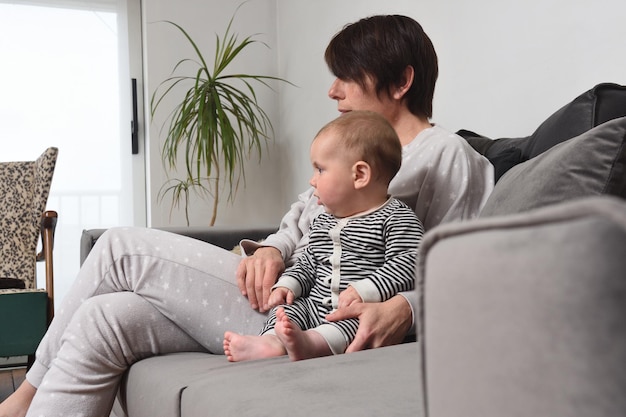 Mother and baby sitting on the sofa staring