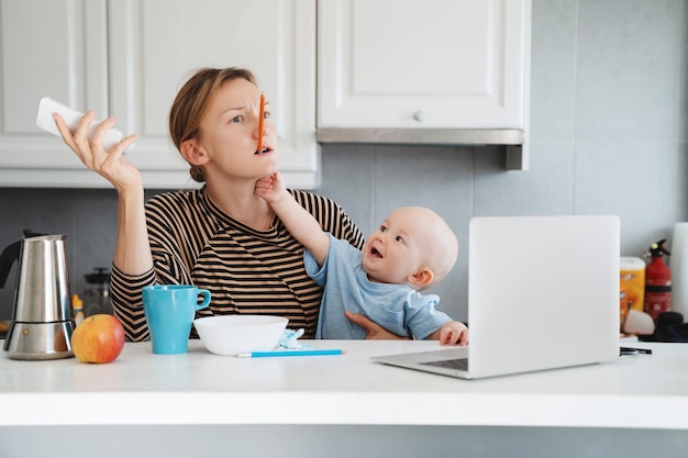 Mother balancing between work and baby on sick or maternity leave Woman responding on phone calls working on laptop computer with child on her lap Woman alone with baby solves problems from home