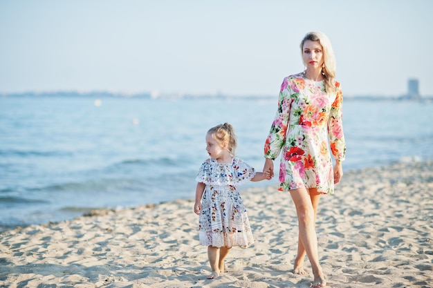 Mother and beautiful daughter having fun on the beach Portrait of happy woman with cute little girl on vacation