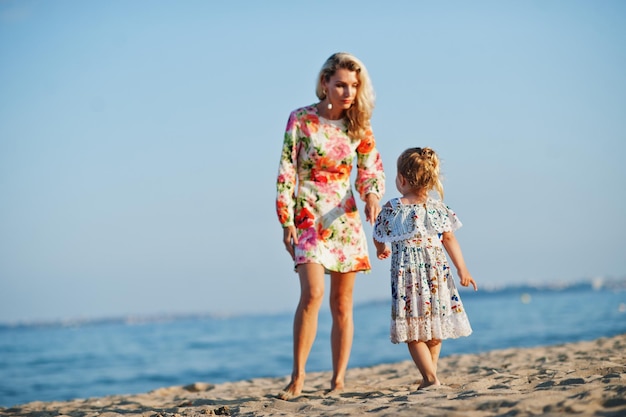 Mother and beautiful daughter having fun on the beach Portrait of happy woman with cute little girl on vacation