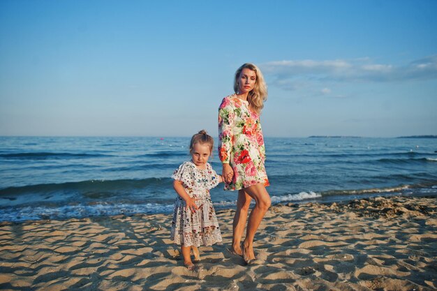 Mother and beautiful daughter having fun on the beach Portrait of happy woman with cute little girl on vacation