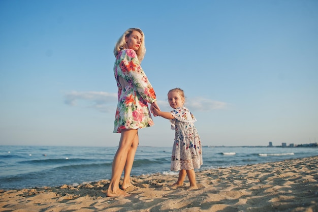 Mother and beautiful daughter having fun on the beach Portrait of happy woman with cute little girl on vacation