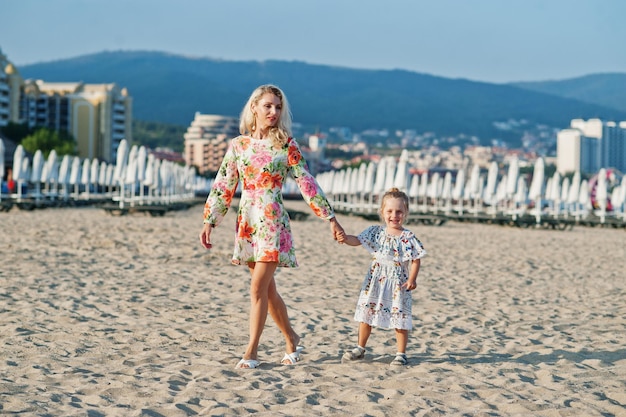 Mother and beautiful daughter having fun on the beach Portrait of happy woman with cute little girl on vacation