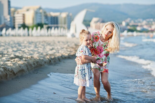 Mother and beautiful daughter having fun on the beach Portrait of happy woman with cute little girl on vacation