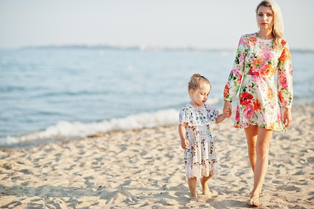 Mother and beautiful daughter having fun on the beach Portrait of happy woman with cute little girl on vacation