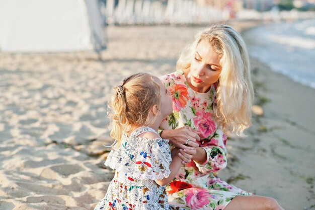 Mother and beautiful daughter having fun on the beach Portrait of happy woman with cute little girl on vacation