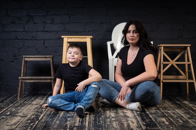 A mother in a black dress holds her son in her arms and sits on a high chair