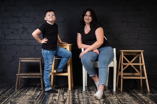 A mother in a black dress holds her son in her arms and sits on a high chair