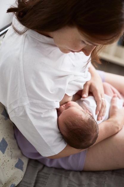 彼女の生まれたばかりの男の子を母乳で育てる母現実的な家の肖像画