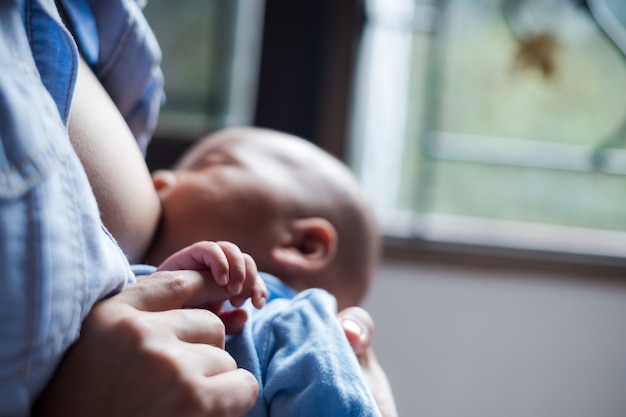 母親の母乳と抱きしめる赤ちゃん。彼女の生まれたばかりの子供を授乳している若いお母さん。