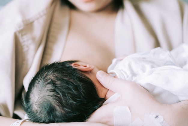 Mother breastfeeding and hugging baby. Young mom breast feeding her newborn child.