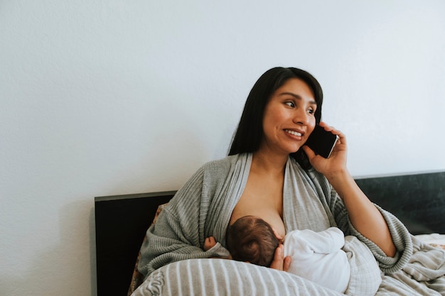 Mamma che allatta al seno mentre è al telefono