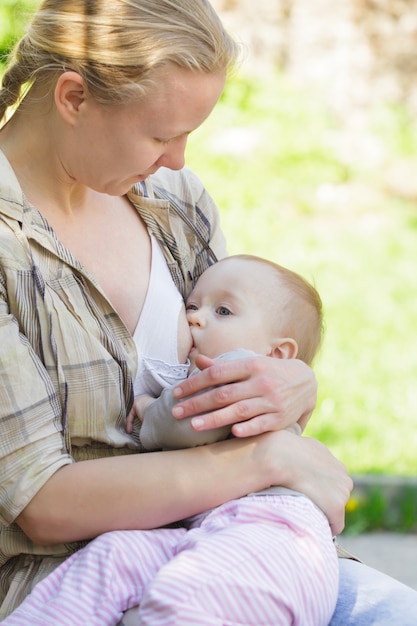 A mother breastfeeds her toddler in the park