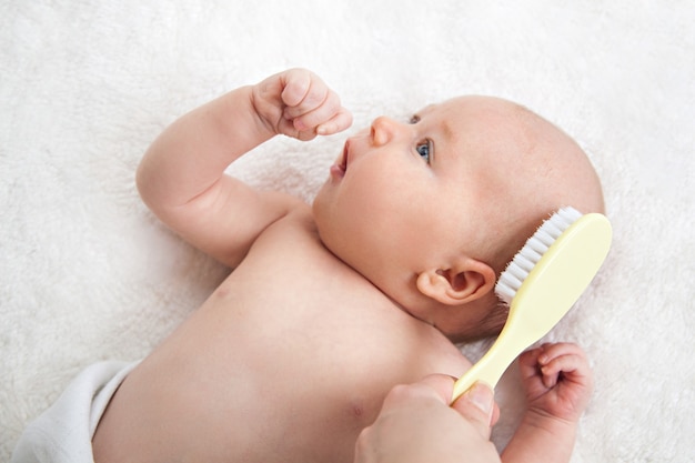 Mother brushing cute baby girl's hair