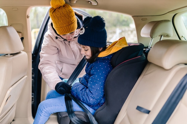 Photo mother buckling up her daughter inside the car