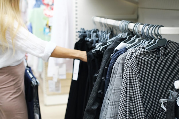 The mother buys clothes for the child for school Young woman chooses a school dress for a girl Horizontal photo