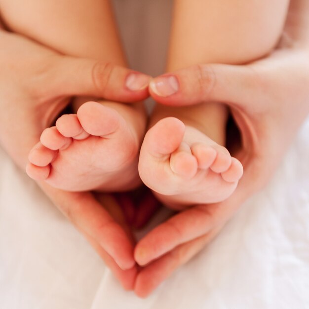 Cura della madre. primo piano vista dall'alto delle mani della madre che toccano le gambe del suo piccolo bambino