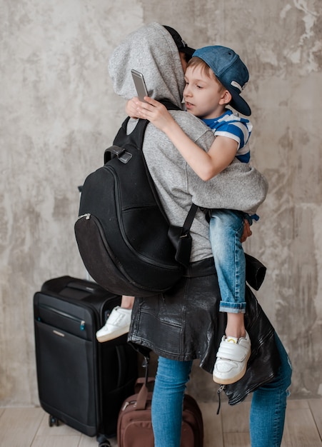 La mamma porta un figlio piccolo su una valigia nella sala d'aspetto del trasporto.