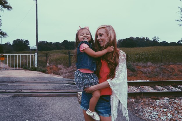 Photo mother carrying daughter against railroad crossing