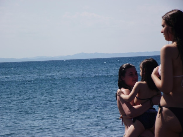 Photo mother carrying daughter by friend at beach during summer