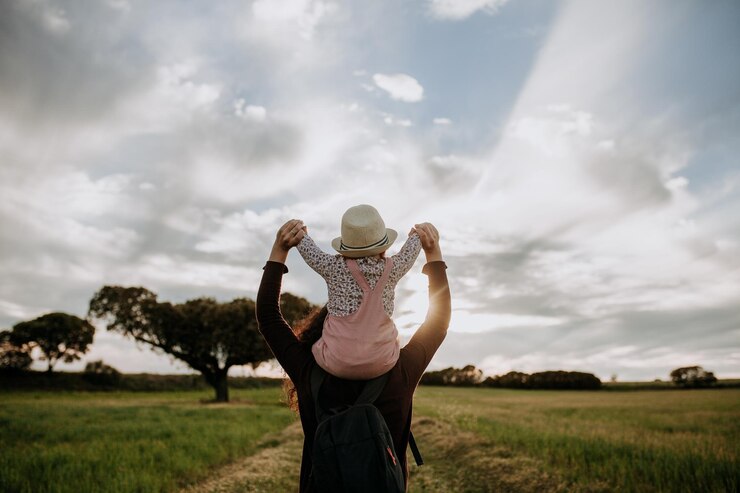 Photo mother carrying daughter on shoulders against cloudy sky