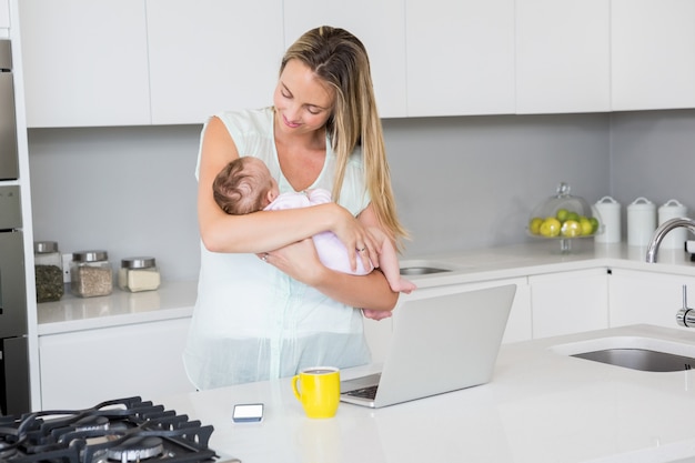 Mother carrying her baby in kitchen