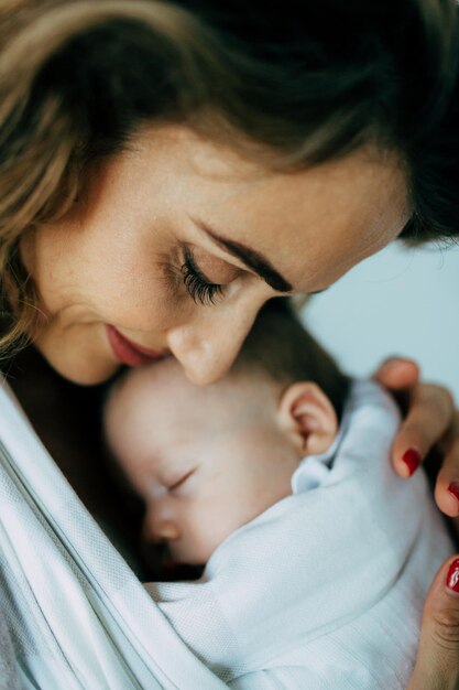 Photo mother carrying newborn son at home