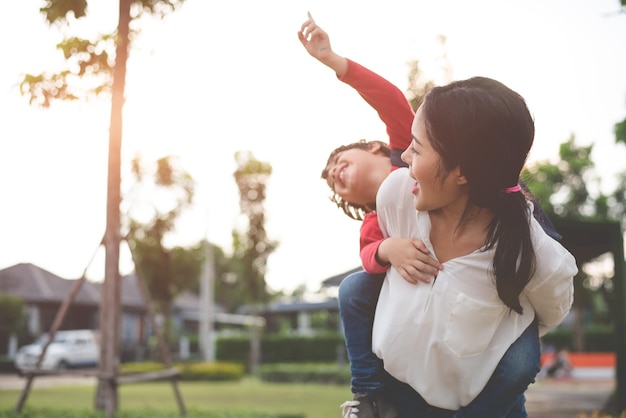 mother carrying playful son at park
