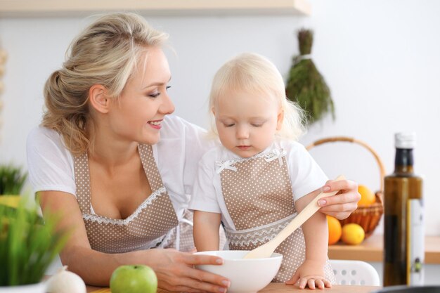 Mother and child daughter  cooking pasta or salad for the breakfast. Concept of happy family in the kitchen.