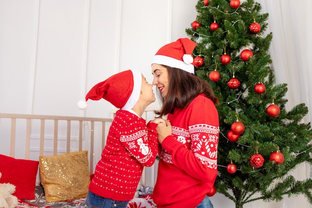 母と子がクリスマスツリーを飾る