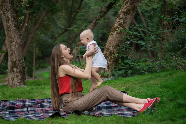 Mother and child enjoying a picnic in the Park. Mom playing with baby fun and laughter