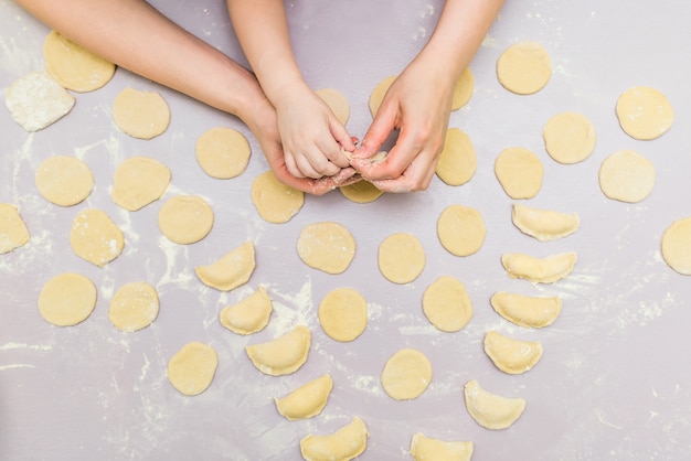 La mano della mamma e del bambino produce i ravioli