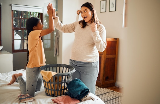 Mother child and high five for laundry basket housework or helping with chores together at home Happy mom and daughter celebrating for clean clothing washing or victory for done or finished work