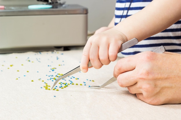 Mother and child make a pattern of beads on the fabric Workplace for handicraft creativity