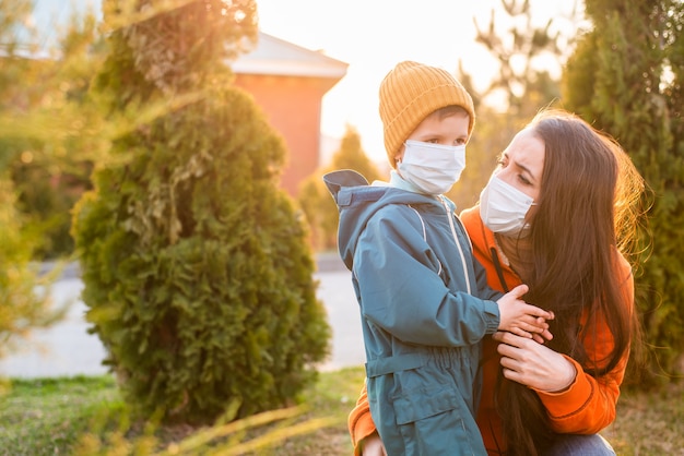 Una madre e un bambino in maschera medica camminano per strada durante il coronavirus e la pandemia di covid-19.