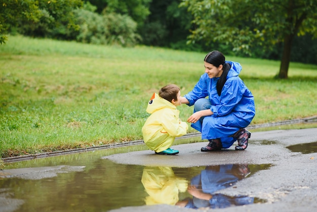 Mother and child playing in the rain, wearing boots and raincoats