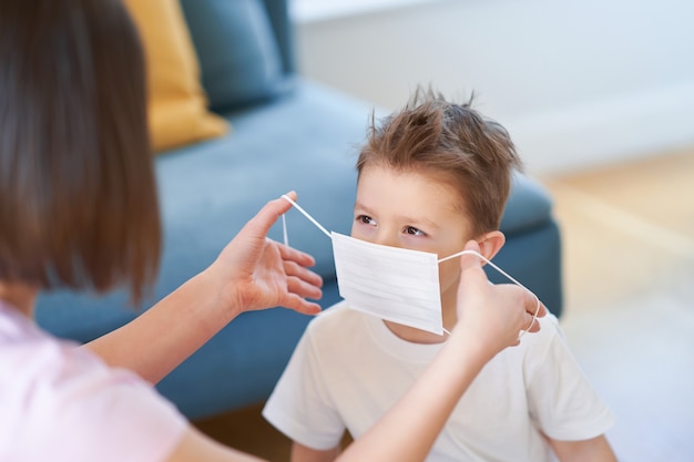 mother and child putting on protective masks during coronavirus pandemic