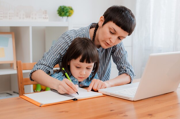 Photo mother and child school student at home on a laptop learning homework ehome schooling during the period of the pandemic and coronavirus