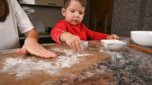 Mother and child sprinkle flour on the baking mat