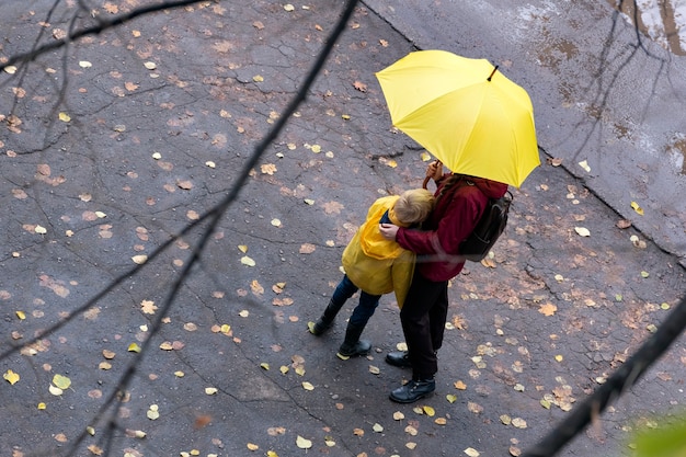 Mother and child standing down the street in the rain. Top view