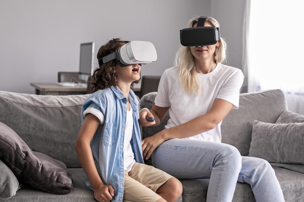 Mother and child wearing virtual reality headset vr glasses in living room at home having fun