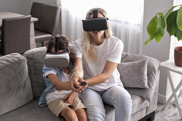 Madre e bambino che indossano occhiali vr per realtà virtuale in soggiorno a casa divertendosi