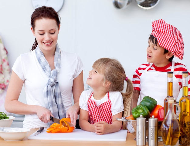 Mother and children cutting peppers in kitchen